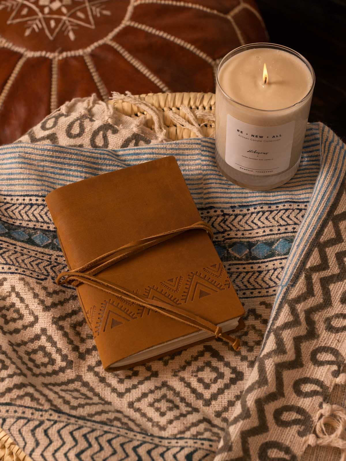 Brown leather triangle journal closed and styled on a patterned textile, highlighting embossed triangle detail and rich leather texture.
