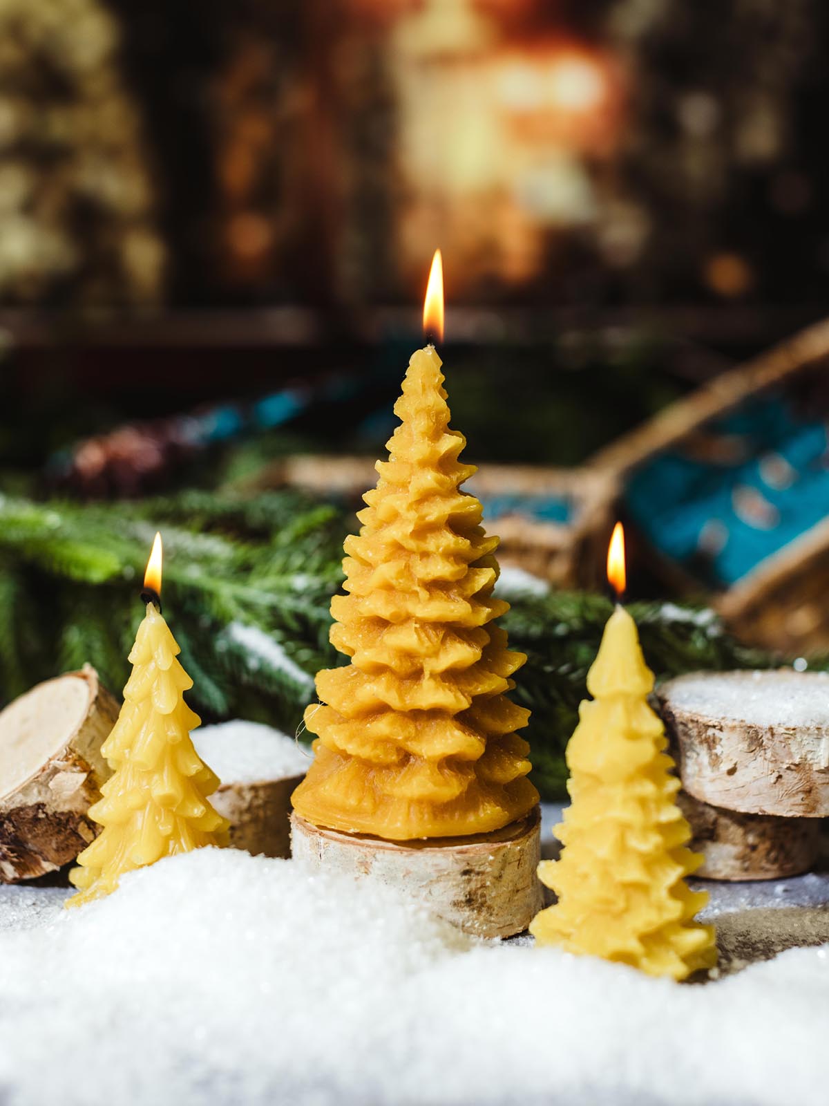 glass scented candle sitting on a wooden pedestal in a rustic holiday greenery setting