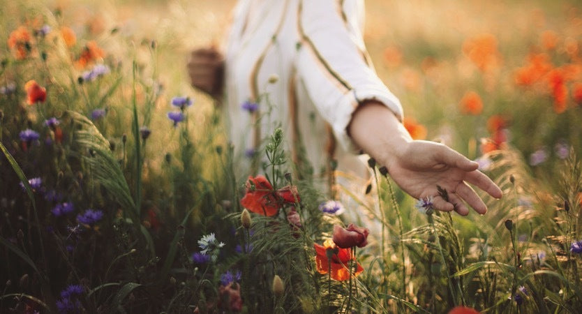 Women in white top walking through a flower phase