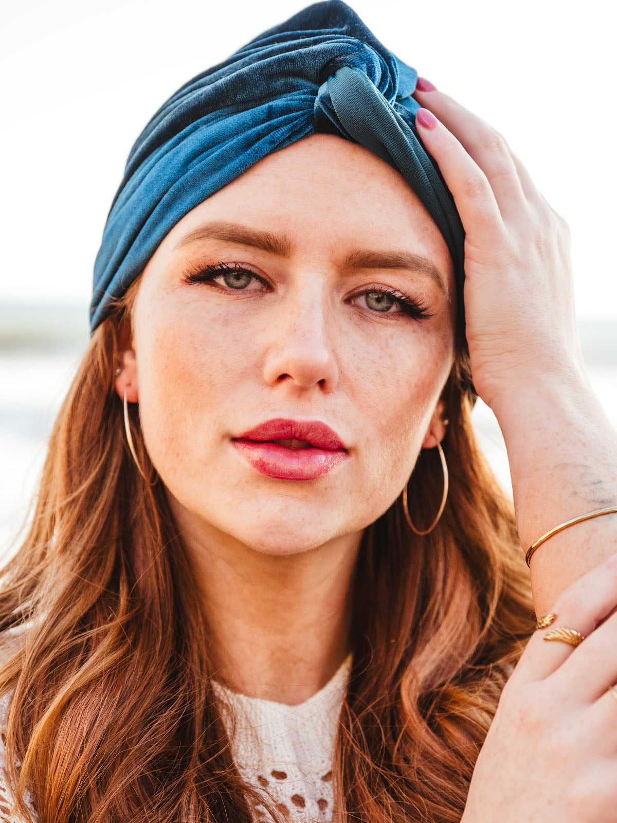 Portrait of female model wearing gold hammered oval shaped earrings. 