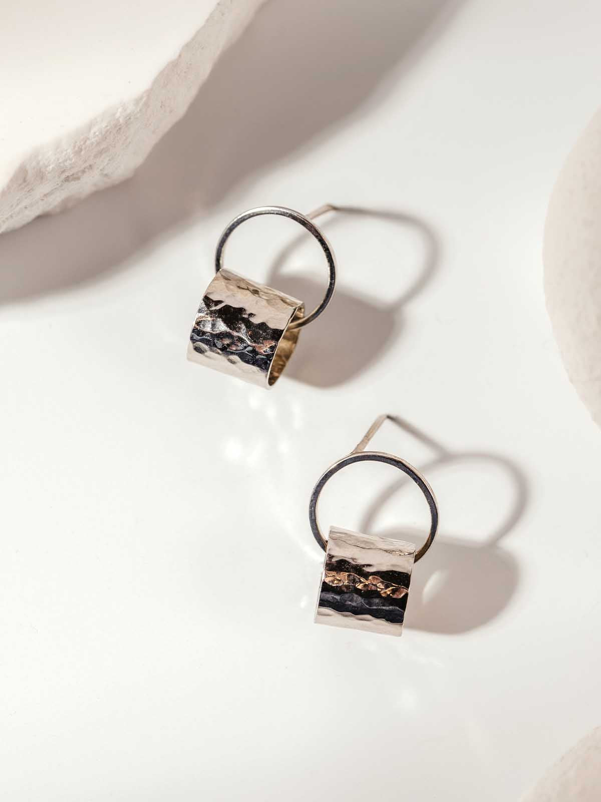 Striped metal hoop earrings with layered metal detail displayed on a neutral surface